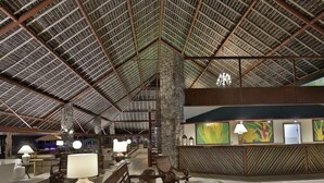 A spacious lobby with a high ceiling, wooden benches, and a reception desk. - Portobello Hotel Resort And Safari (Mangaratiba)