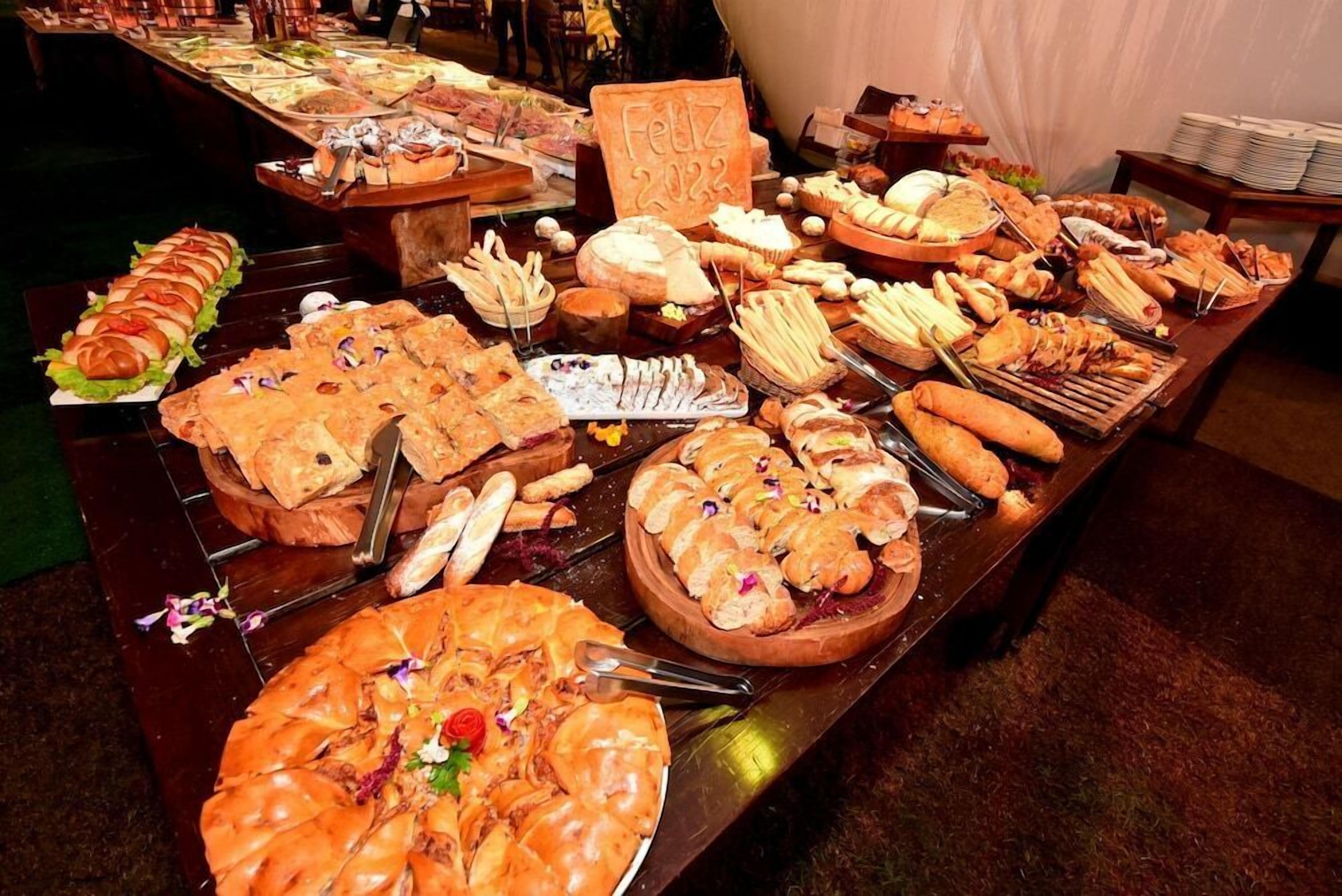 Mesa de buffet com diversos alimentos e uma placa que diz 'Feliz 2022'.