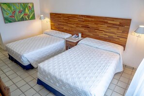 Quarto de hotel com duas camas, cabeceira de madeira, luminárias de cabeceira e um quadro na parede.