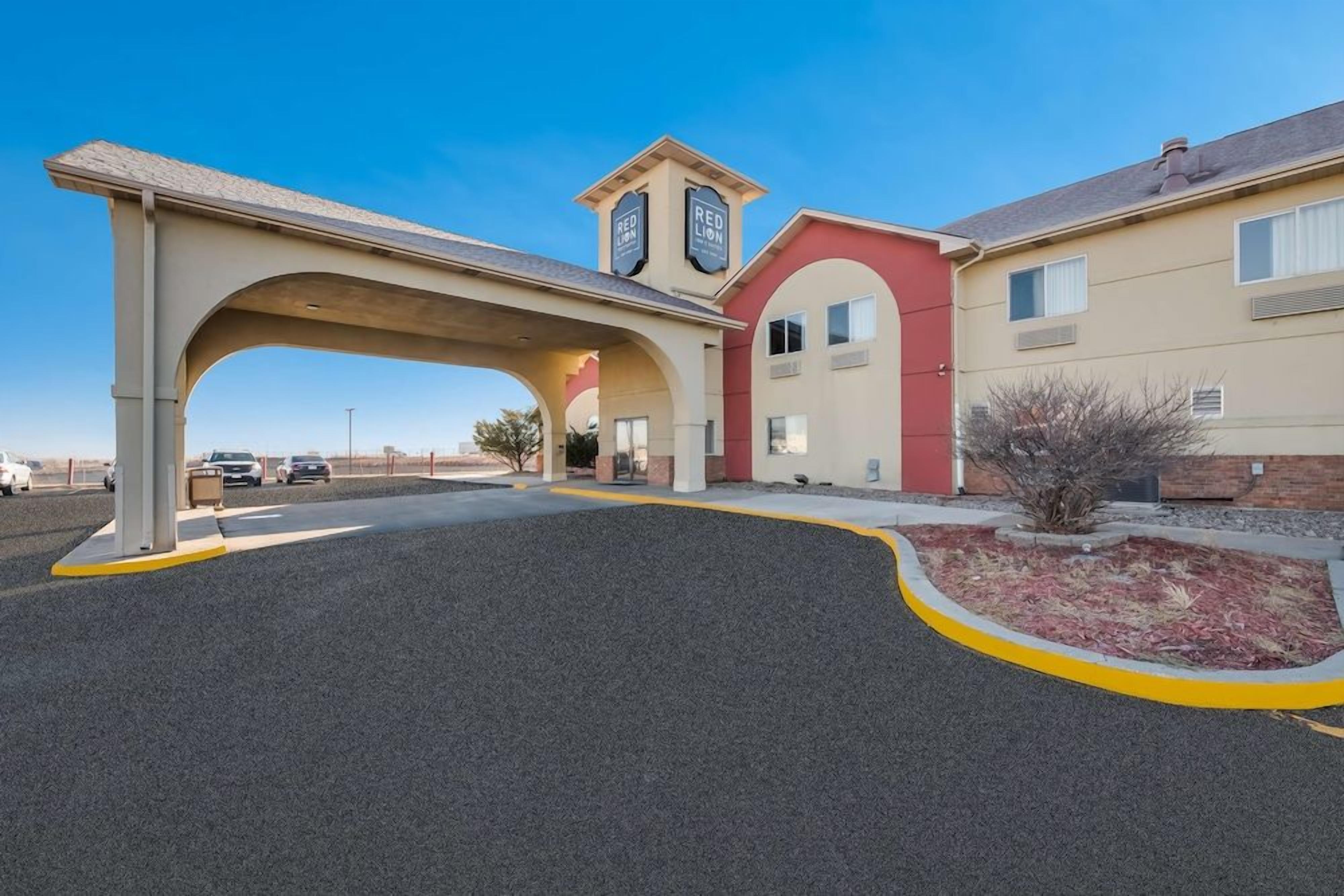 A Red Lion hotel with a covered parking area, a red and beige building, and a clear sky.