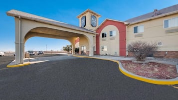 A Red Lion hotel with a covered parking area, a red and beige building, and a clear sky.