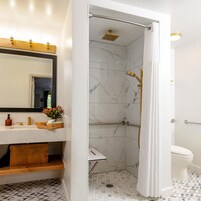 Un baño con ducha, inodoro y tocador con espejo y lavamanos.