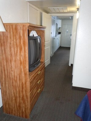 A hallway with a wooden cabinet containing a microwave, a door, and a carpeted floor. - Travelodge by Wyndham Grand Rapids North (Grand Rapids)