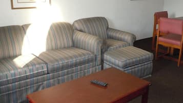 A living room with a striped sofa, a wooden coffee table, and a wooden chair.