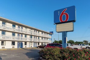 A motel with a prominent sign, a parking lot, and a building with multiple windows and balconies. - Motel6 Cincinnati, OH (Sharonville)