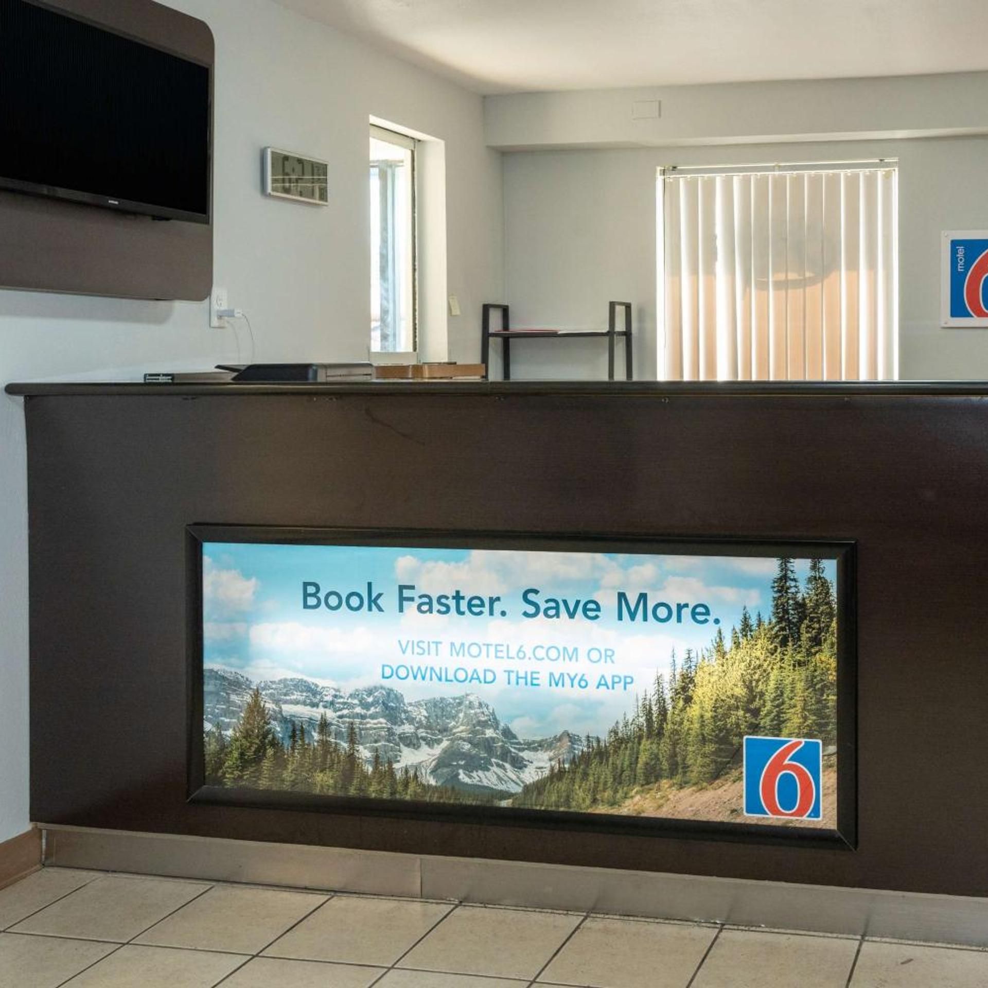 A reception desk with a digital screen displaying a booking message.