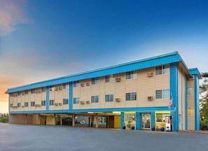 A two-story motel with a flat roof, multiple parking spaces, and a gas station on the ground floor. - Hotel Roseburg (Roseburg)