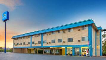 A hotel with a flat roof, multiple windows, and a parking lot.