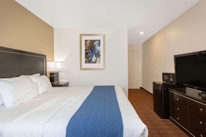 A hotel room with a bed, a TV, a desk with a lamp, and a picture on the wall. - Baymont by Wyndham Roseburg (Roseburg)
