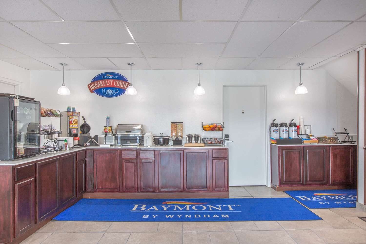 A breakfast bar with a Baymont sign, a coffee machine, and a waffle maker.