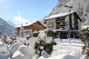 A hotel with a sign indicating it is a restaurant and hotel, surrounded by snow-covered trees and mountains. - Typically Swiss Hotel Tascherhof (Taesch)