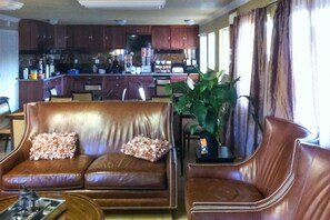 A living room with a brown leather sofa, a coffee table, and a potted plant. - First Interstate Inn (Grand Junction)
