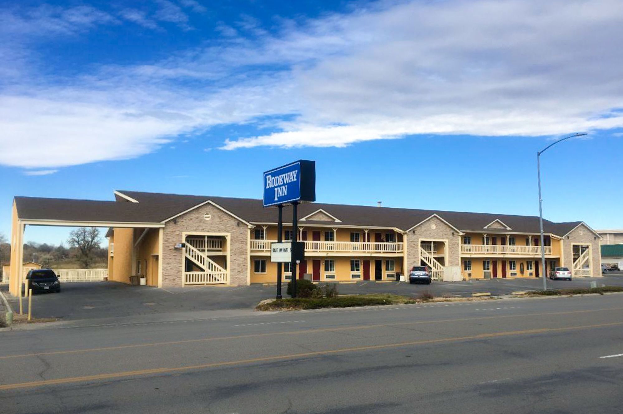 A motel with a covered parking area, a signboard, and a multi-story building with balconies.