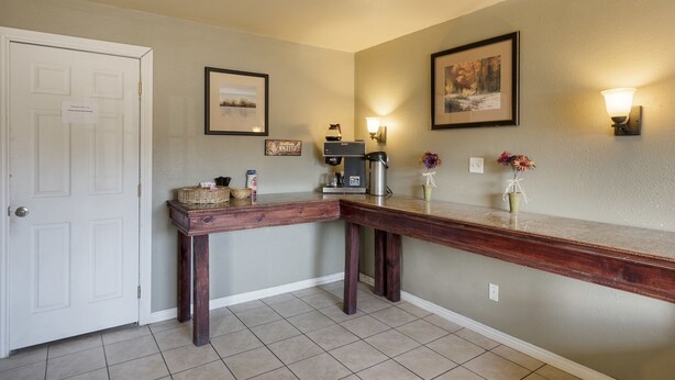 A hallway with a coffee station, framed artwork, and a door. - First Interstate Inn (Grand Junction)