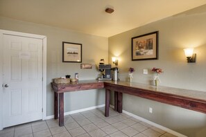 Un couloir avec un coin café, des œuvres d’art encadrées et une porte.