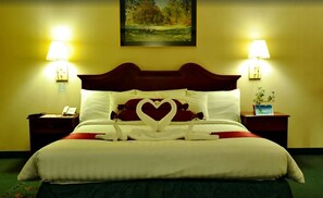 A hotel room with a large bed, two bedside lamps, a painting on the wall, and a small table with a plant. - Days Hotel Batangas (Batangas City)