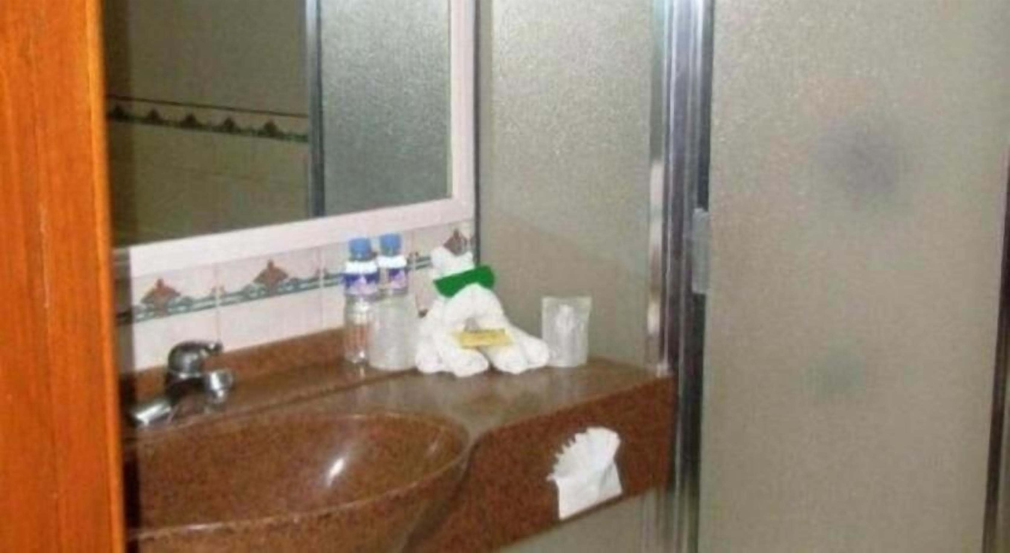 A bathroom with a granite sink, a mirror, a towel rack, and a glass of water.