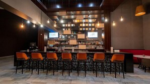 A bar area with multiple stools, a counter, and overhead lighting.