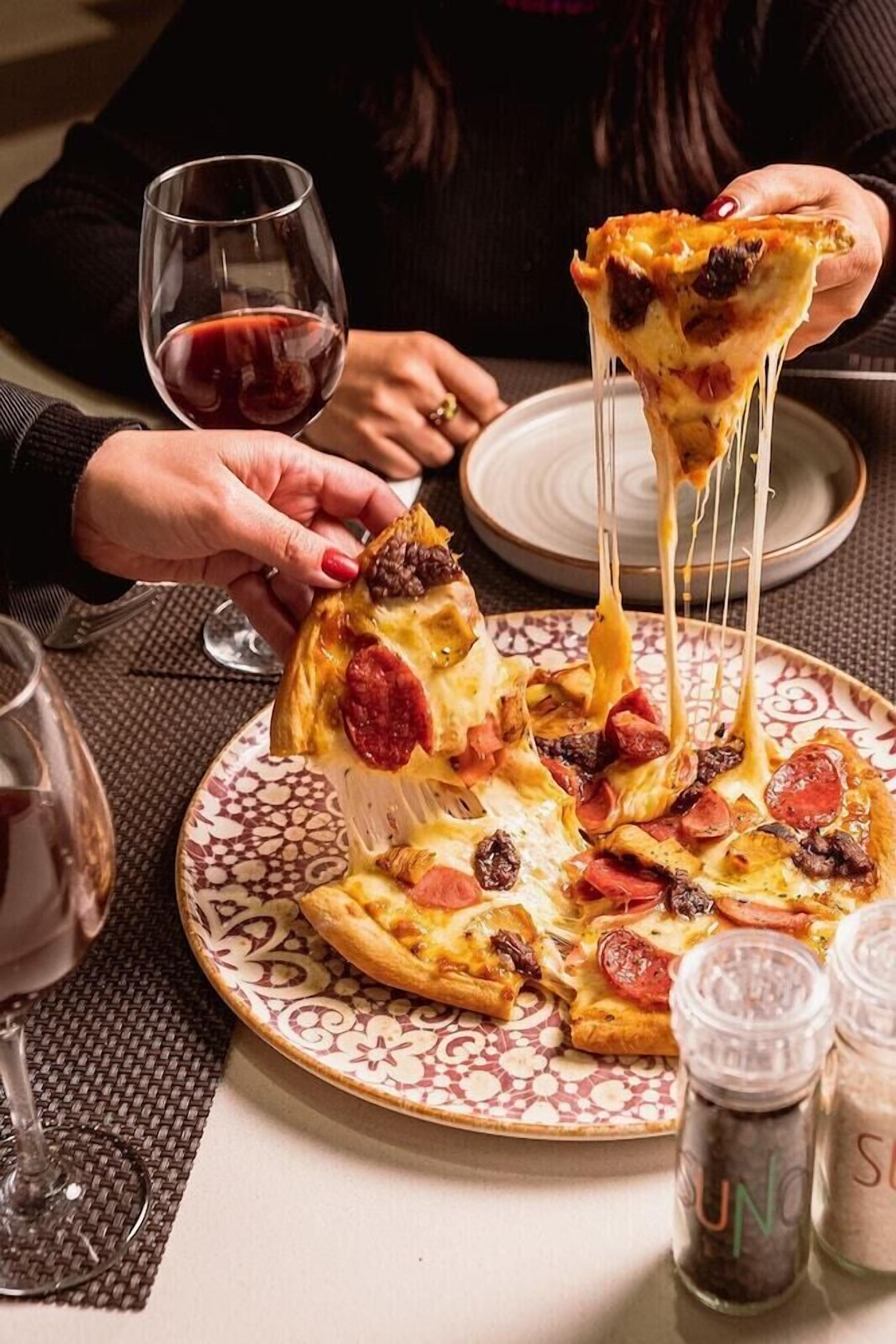 A pizza with toppings being lifted from a plate.