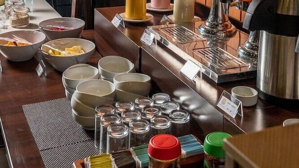 A buffet setup with various food items, a coffee machine, and a juice dispenser.