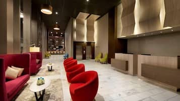 A modern lobby with red seating, a reception desk, and a marble floor.