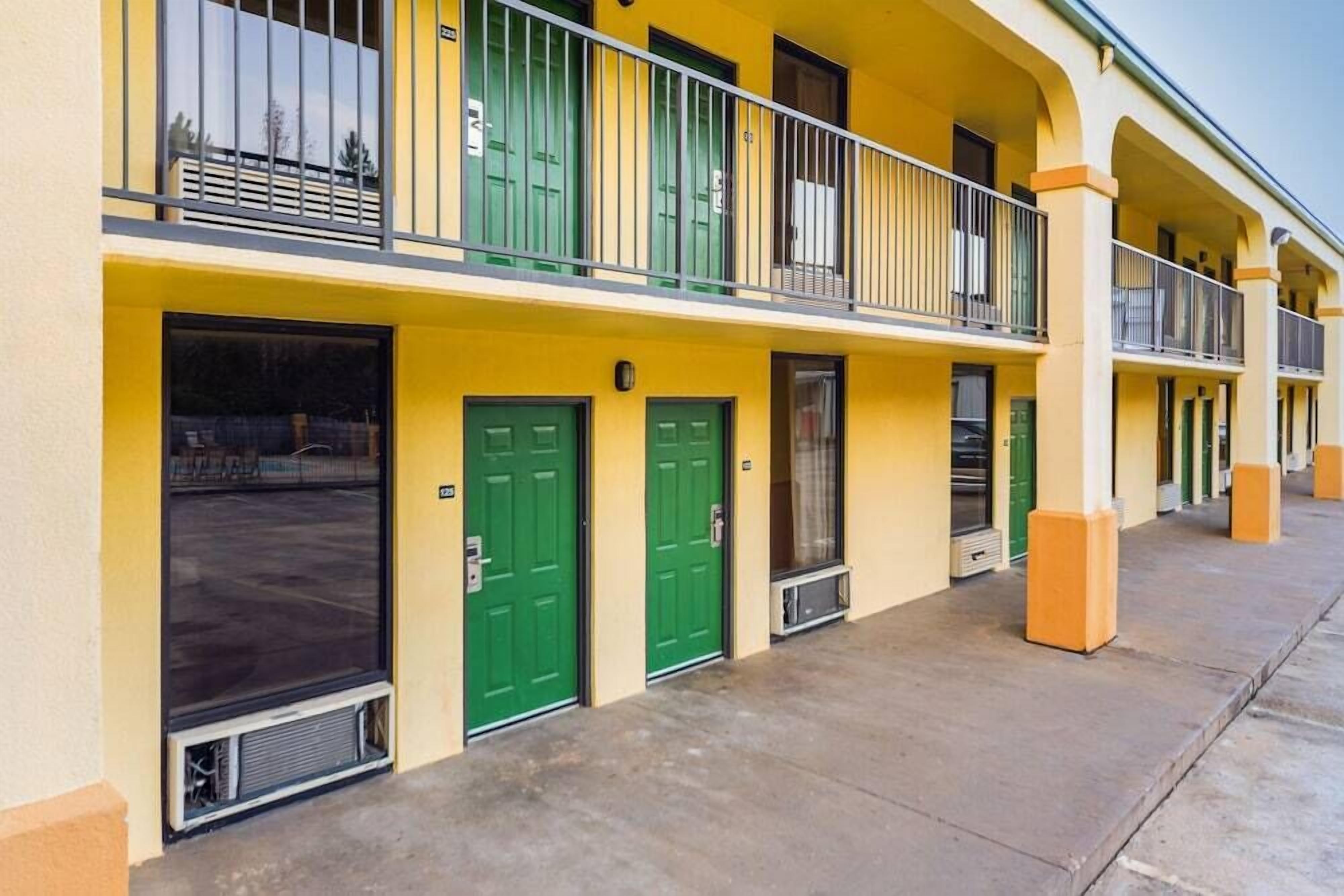 A row of yellow buildings with green doors and balconies.