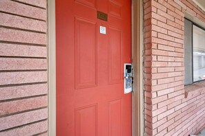 A red door with a number plate, a keypad lock, and a window to the right. - OYO Hotel Beeville US 181 (Beeville)