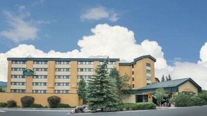 Un hôtel à plusieurs étages, doté d’une enseigne bien visible, d’un parking et d’un espace paysager agrémenté d’un arbre.