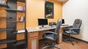 Une chambre d’hôtel équipée d’un bureau, de deux chaises, d’une bibliothèque et d’une affiche au mur.