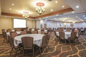 A conference room with round tables, chairs, a projector screen, and chandeliers. - La Quinta Inn & Suites by Wyndham Silverthorne - Summit Co (Silverthorne)