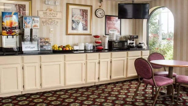A breakfast bar with a clock, a TV, and a window with a view of greenery. - Econo Lodge Chesapeake Route 13 and I-464 (Chesapeake)