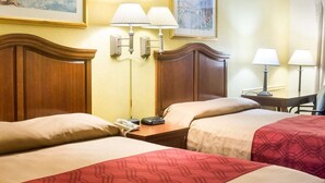 A hotel room with two beds, a wooden headboard, bedside lamps, a telephone, and a painting on the wall. - Econo Lodge Chesapeake Route 13 and I-464 (Chesapeake)