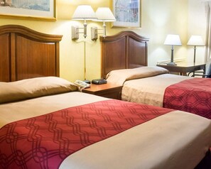 A hotel room with two beds, a wooden headboard, bedside lamps, a telephone, and a painting on the wall. - Econo Lodge Chesapeake Route 13 and I-464 (Chesapeake)