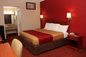 Ein Hotelzimmer mit Bett, Nachttisch, Lampe und Spiegel.