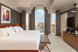 A hotel room with a large bed, a bench, a TV, a coffee machine, and a view of the city through a balcony. - Art Hotel Novecento (Bologna)