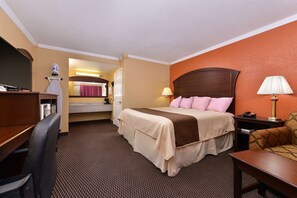 A hotel room with a bed, desk, chair, and a bathroom visible through an open door. - Americas Best Value Inn Schulenburg (Schulenburg)
