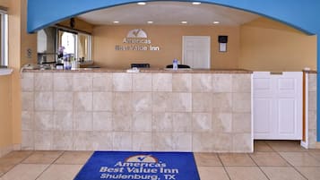 A reception area with a counter, a door labeled 'Employees Only,' and a blue mat with the hotel's name and location.
