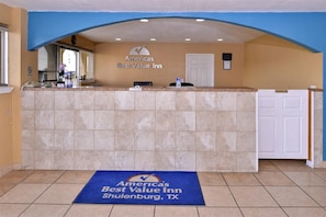 A reception area with a counter, a door labeled 'Employees Only,' and a blue mat with the hotel's name and location. - Americas Best Value Inn Schulenburg (Schulenburg)