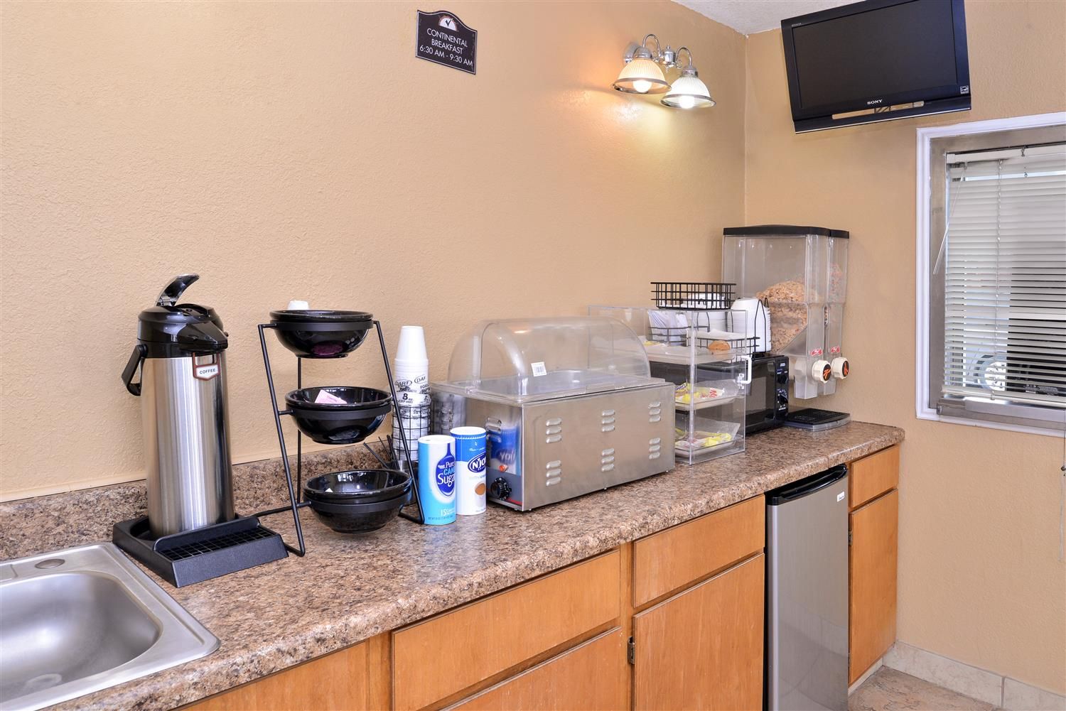 A kitchenette with a coffee maker, sugar dispenser, and a toaster.