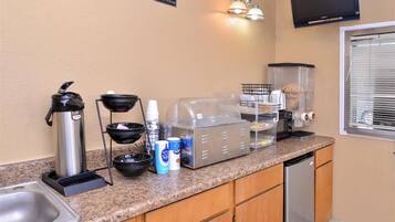 A kitchenette with a coffee maker, sugar dispenser, and a toaster.