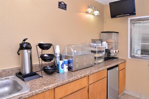 Una kitchenette equipada con cafetera, dispensador de azúcar y tostadora.
