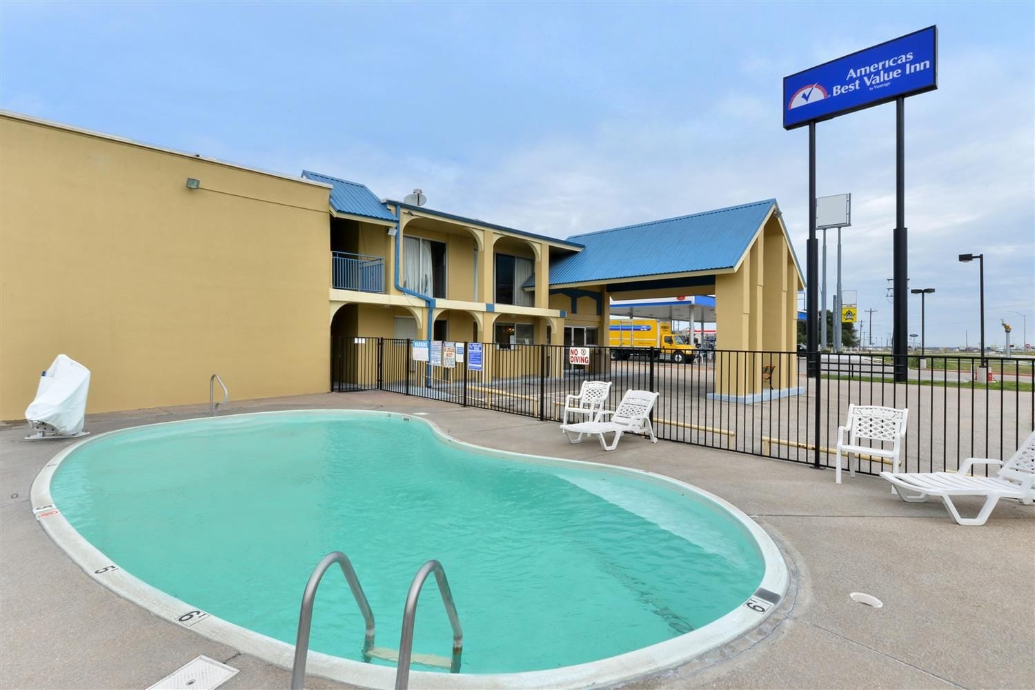 A swimming pool with lounge chairs and a sign for Americas Best Value Inn.