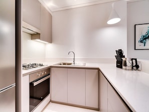 Eine moderne Küche mit Gasherd, Backofen, Spüle und einer Arbeitsfläche mit Kaffeemaschine und Messerblock.