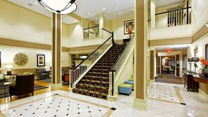 A spacious lobby with a grand staircase, a chandelier, and a tiled floor. - Country Inn & Suites By Radisson Evansville IN (Evansville)