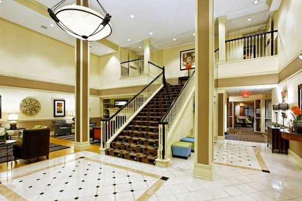 A spacious lobby with a grand staircase, a chandelier, and a tiled floor. - Country Inn & Suites By Radisson Evansville IN (Evansville)