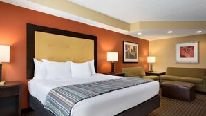 A hotel room with a large bed, two bedside tables, a sofa, and a patterned carpet. - Country Inn & Suites By Radisson Evansville IN (Evansville)