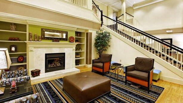 A spacious living area with a fireplace, a staircase, and a variety of furniture. - Country Inn & Suites By Radisson Evansville IN (Evansville)