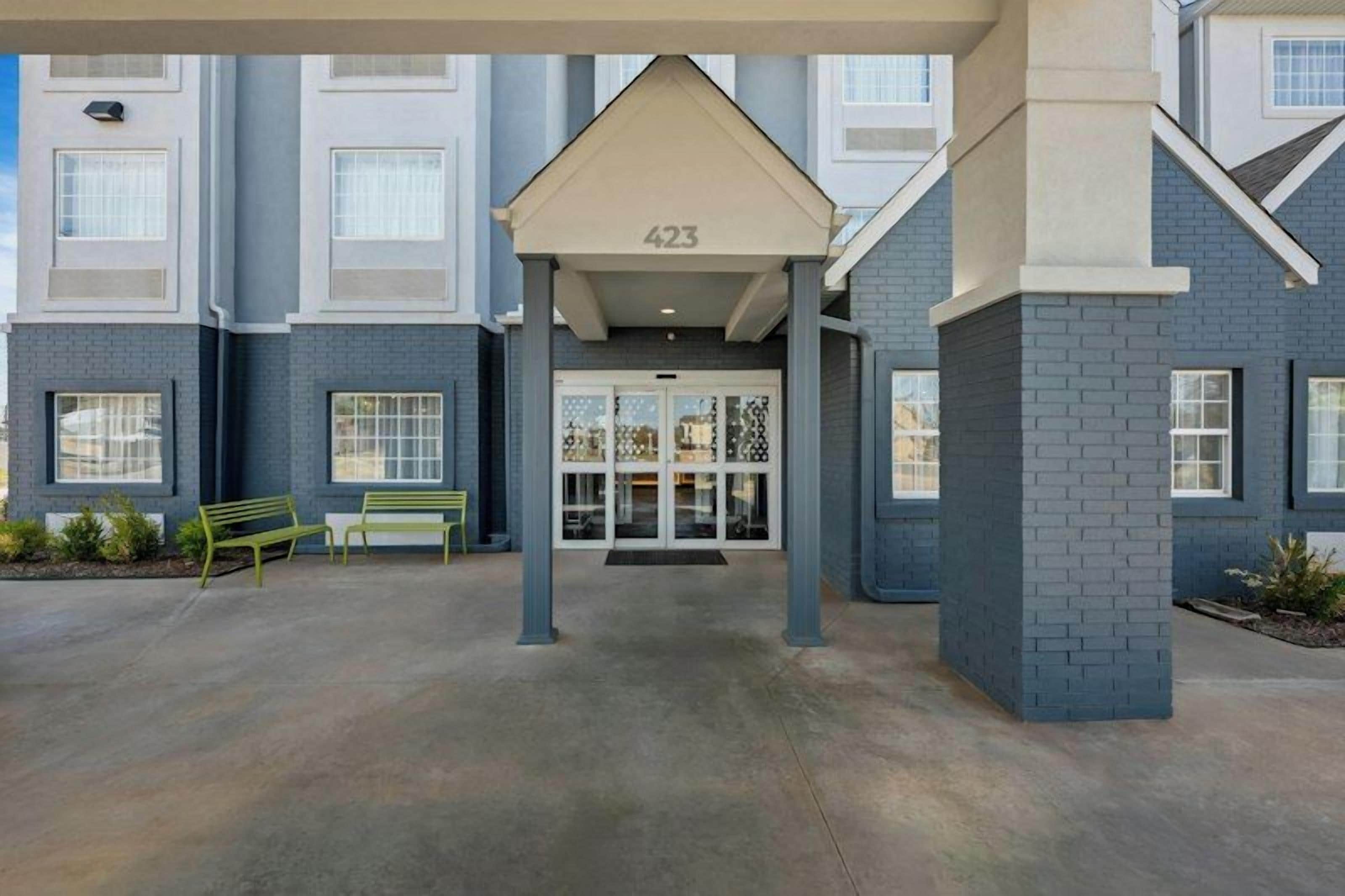 A building entrance with a covered walkway, numbered 423, and a bench to the left.
