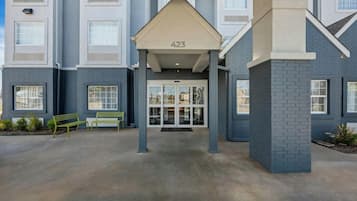 A building entrance with a covered walkway, numbered 423, and a bench to the left.