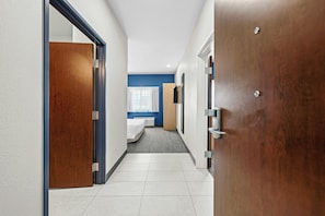 A hotel corridor with a bed, a window with curtains, and a door. - Spark by Hilton Stillwater (Stillwater)